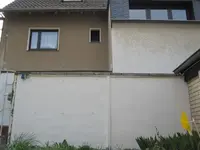 Blick von der Terrasse über die Mauer hinweg zum Nachbarhaus.webp